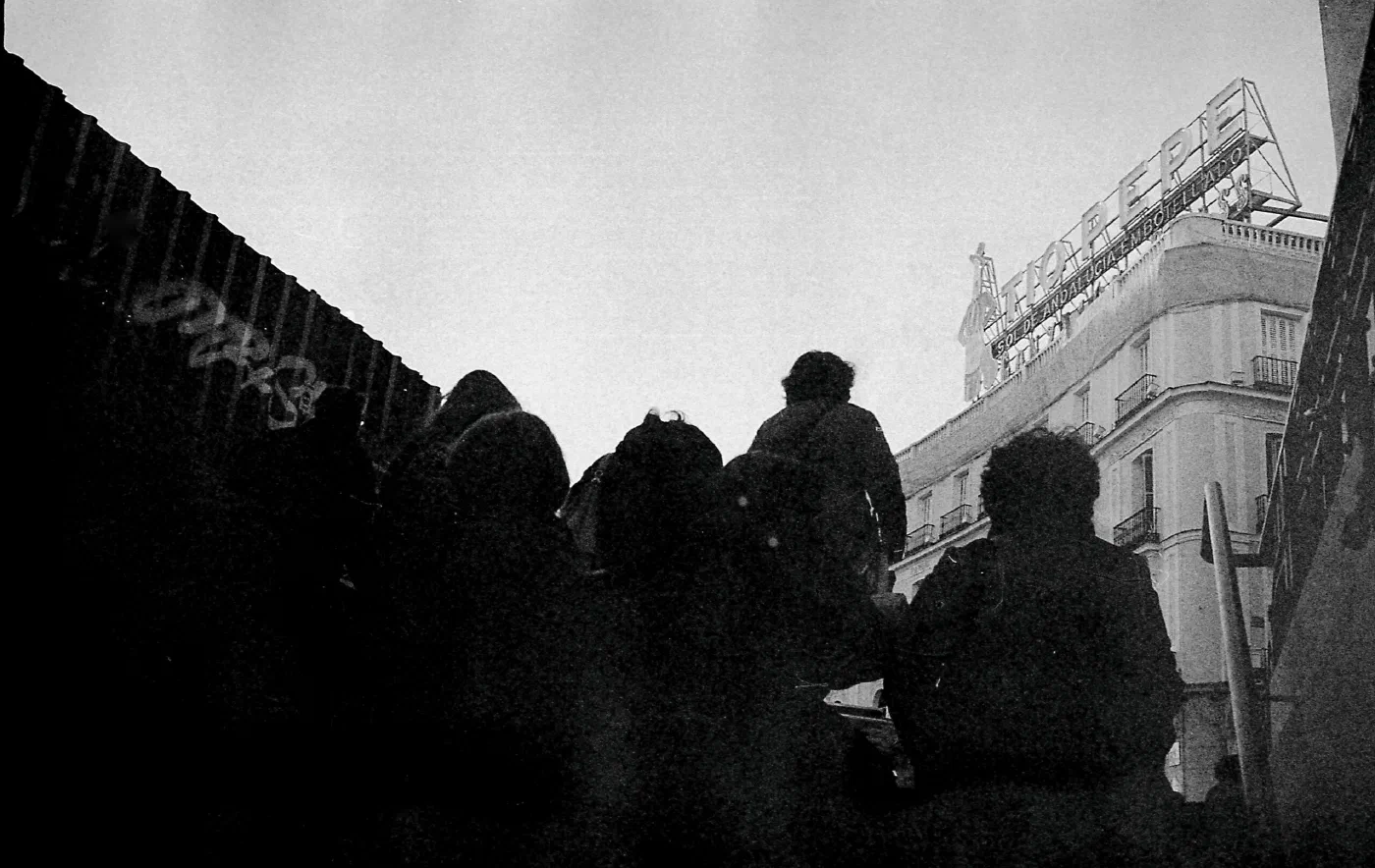 Black and white picture of people leaving the Sol metro station in Madrid with the Tío Pepe sign in the background